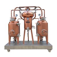 a red copper distiller composed of two pot stills, one heat exchanger and accessories mounted on a skid