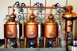 three red copper pot stills and one red copper heat exchanger on a skid, distillate flows from condenser and stored in the barrel